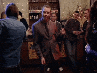 a man in a suit and tie is dancing in a crowded room
