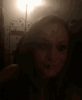 a woman is taking a selfie in the dark with a lamp in the background .