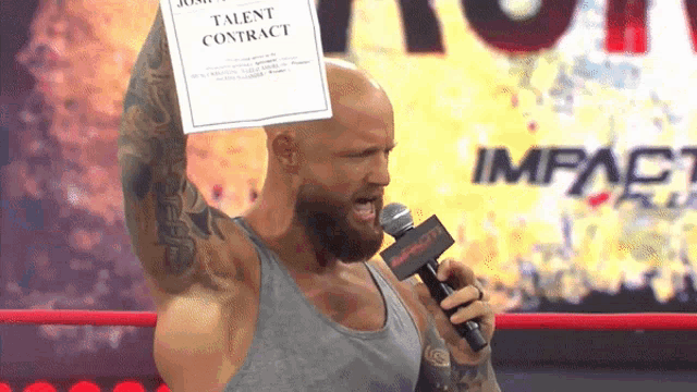 a man in a wrestling ring holds a talent contract over his head