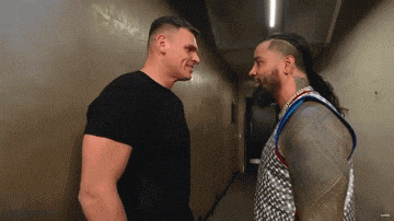 two men are facing each other in a hallway and one of them has a tattoo on his arm