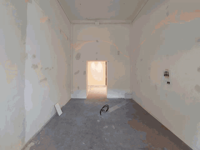an empty room with a ladder and a bucket of paint on the floor