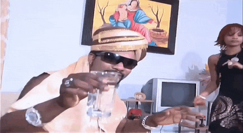 a man wearing sunglasses and a hat is holding a glass