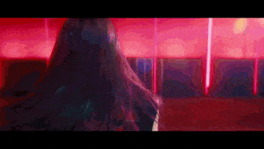 a woman with long black hair is standing in a room with red lights behind her .