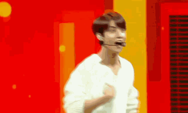 a man in a white shirt is dancing on a stage with a microphone in his mouth .
