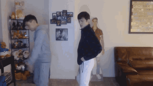 two men are dancing in a living room with a love sign on the wall
