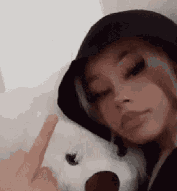 a woman is holding a stuffed animal and giving the middle finger .