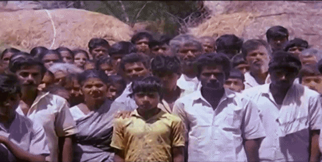 a group of people are standing in front of a large rock