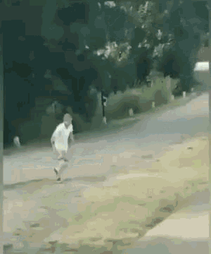 a man in a white shirt is running down a sidewalk .