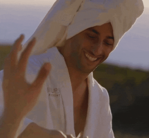 a man with a towel wrapped around his head is wearing a white robe that says u/up retreat