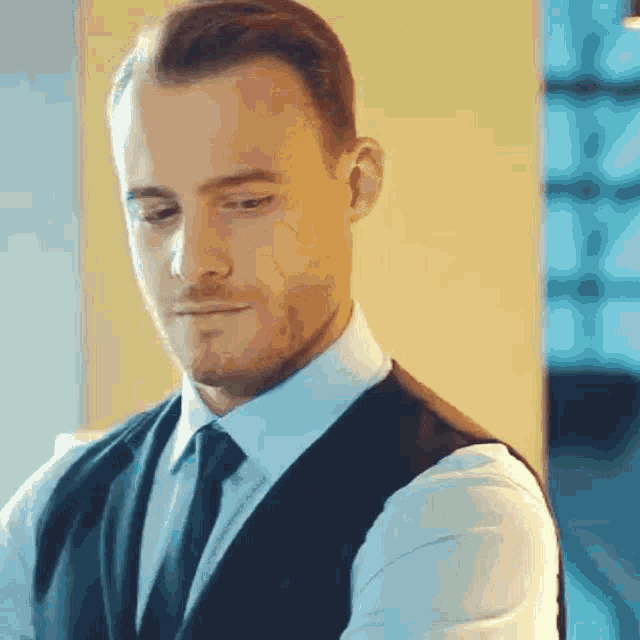 a man wearing a suit and tie is looking down