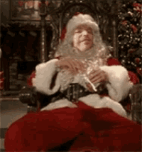 a man dressed as santa claus is sitting in a chair drinking a beer