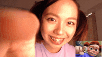 a woman in a purple shirt is pointing at a picture of a puppet