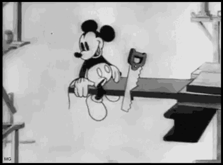 mickey mouse is sitting on a shelf with a saw in his hand .