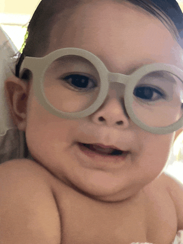 a baby wearing glasses looks at the camera