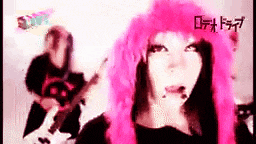 a girl with pink hair is playing a guitar in a band