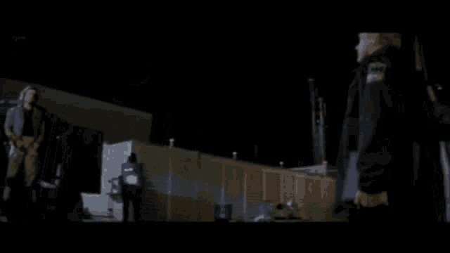 a man is standing in front of a building at night holding a rifle .