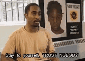 a man in a tan shirt is sitting in front of a poster that says `` stay to yourself , trust nobody '' .