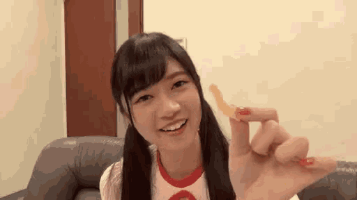 a young woman is holding a piece of french fries in her hand and smiling .