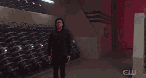 a man in a black shirt is dancing in front of a cw logo