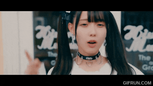 a girl with pigtails and a choker stands in front of a window that says ' the '