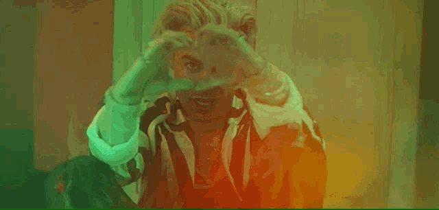 a man in a suit and tie is making a heart with his hands .