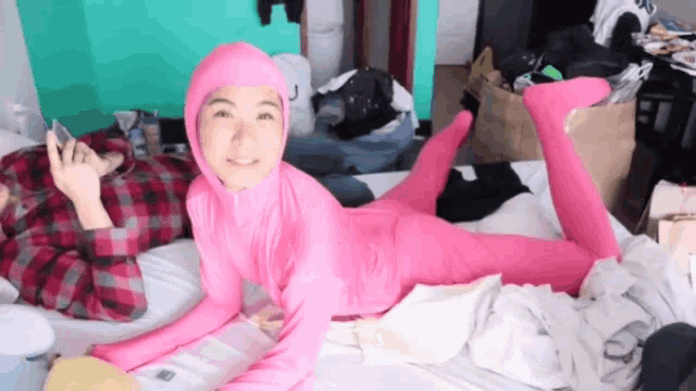 a girl in a pink bodysuit is laying on a bed