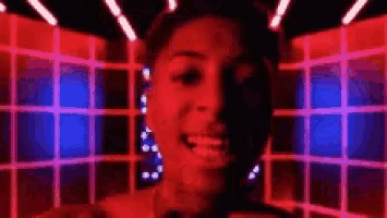 a close up of a person 's face in a dark room with red and blue lights .
