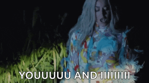 a woman in a colorful dress is standing in a field with the words `` youuu and ii '' written on the ground .