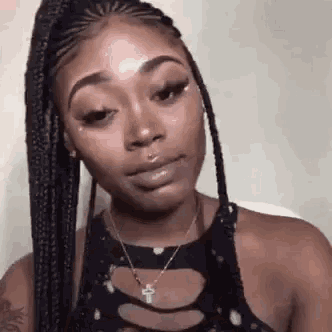 a woman with braids is wearing a black top and a necklace .