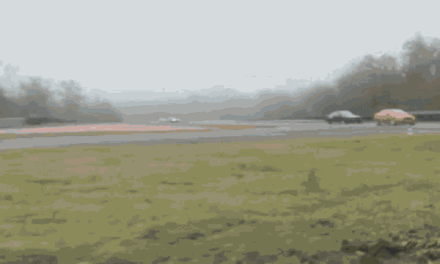 a blurred image of a race track with a red car in the distance