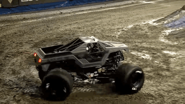 a monster truck is driving on a dirt track with a sign in the background that says ' lucky '
