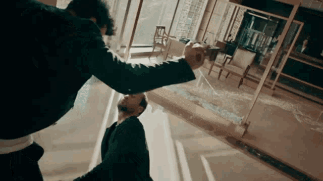 a man in a suit is being punched in the face by another man in a suit