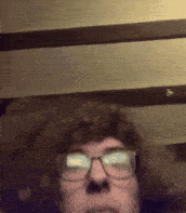 a man wearing glasses and a big afro looks at the camera