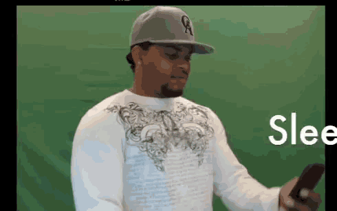 a man wearing a baseball cap is holding a cell phone