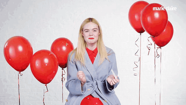a woman stands in front of a bunch of red balloons with marieclaire written in the corner