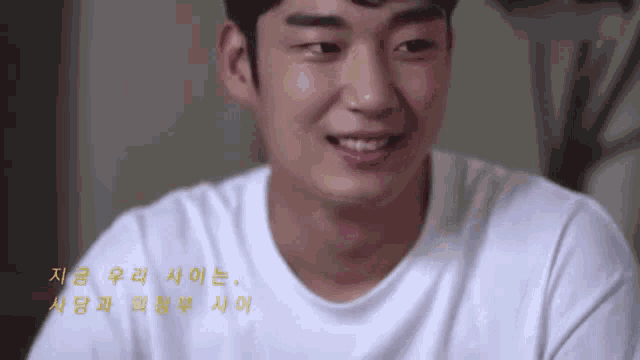 a man in a white shirt is smiling and looking at the camera