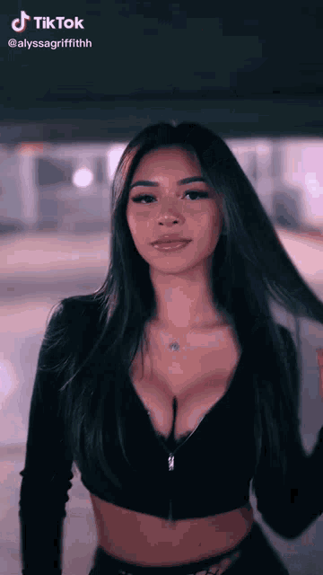 a woman with long dark hair is wearing a black crop top with a plunging neckline