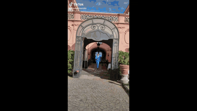 a man in a light blue suit and tie is standing on a cobblestone street .
