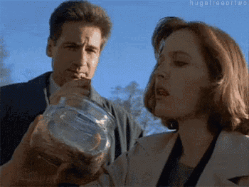 a man and a woman are standing next to each other and the woman is holding a jar of money