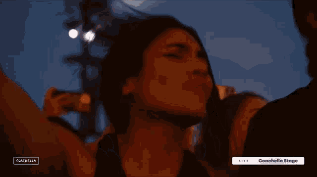 a woman in a black dress stands in front of a screen that says coachella
