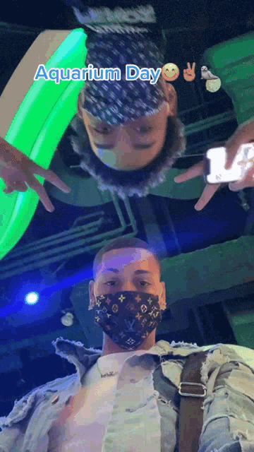 a man wearing a louis vuitton mask is taking a selfie with another man in an aquarium
