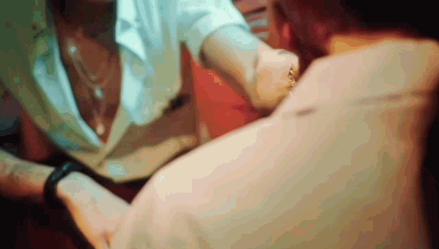 a woman is holding a man 's hand while looking at his watch .