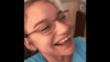 a woman wearing glasses and a blue shirt is smiling .
