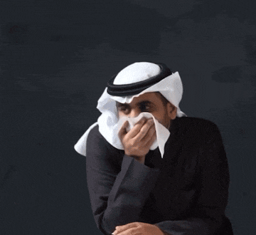 a man wearing a head scarf and covering his mouth with a napkin