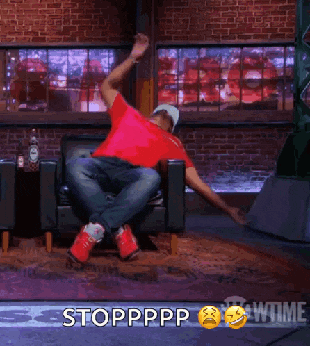 a man in a red shirt is sitting in a chair with his arms outstretched and the words stoppppp behind him