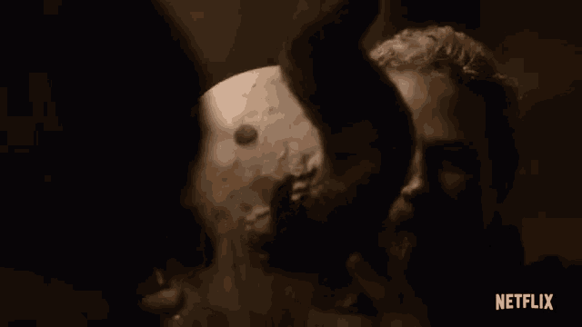 a man with a beard is holding a statue in a dark room in a netflix trailer .