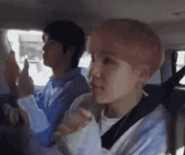a man is sitting in the back seat of a car while another man looks out the window .