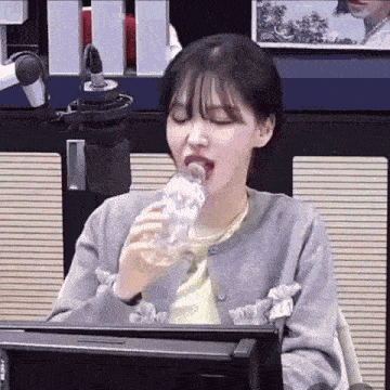 a woman is drinking water from a plastic bottle in front of a microphone .