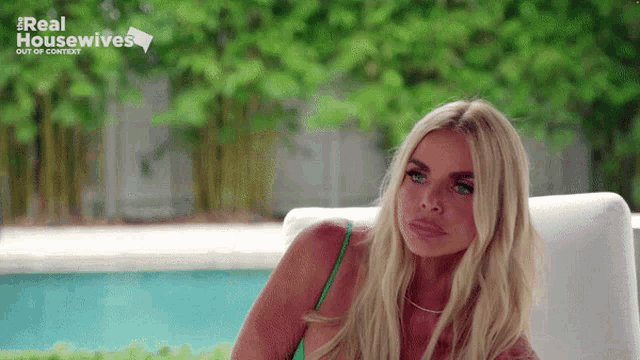 a woman in a green bikini is sitting in front of a pool with the words real housewives out of context