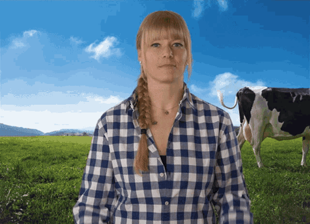 a woman in a plaid shirt stands in a grassy field with a cow in the background